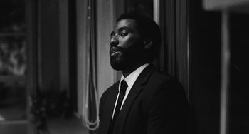 Movie still from “Malcolm & Marie” (2021), directed by Sam Levinson – A man wearing a suit and tie in front of a window; Close Up shot, Low angle