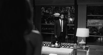 Movie still from “Malcolm & Marie” (2021), directed by Sam Levinson – A black and white photo of a man in a suit and tie; Medium shot, Over the shoulder angle