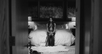 Movie still from “Malcolm & Marie” (2021), directed by Sam Levinson – A black and white photo of a woman sitting on a bed; Wide shot, High angle