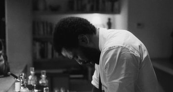 Movie still from “Malcolm & Marie” (2021), directed by Sam Levinson – A black and white photo of a man looking down; Close Up shot, Over the shoulder angle