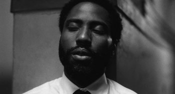 Movie still from “Malcolm & Marie” (2021), directed by Sam Levinson – A black and white photo of a man with his eyes closed; Close Up shot, Low angle