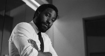 Movie still from “Malcolm & Marie” (2021), directed by Sam Levinson – A black and white photo of a man with his arms crossed; Close Up shot, Low angle