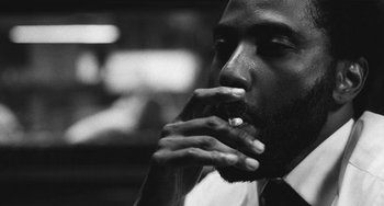 Movie still from “Malcolm & Marie” (2021), directed by Sam Levinson – A black and white photo of a man smoking a cigarette; Extreme Close Up shot, Low angle