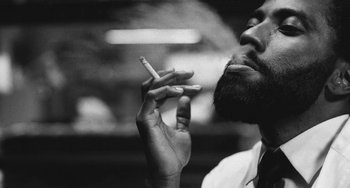 Movie still from “Malcolm & Marie” (2021), directed by Sam Levinson – A black and white photo of a man smoking a cigarette; Close Up shot, Low angle