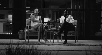 Movie still from “Malcolm & Marie” (2021), directed by Sam Levinson – A man and a woman sitting on a chair outside; Medium shot, Low angle