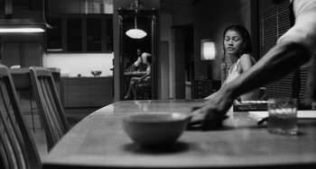 Movie still from “Malcolm & Marie” (2021), directed by Sam Levinson – A woman sitting at a table with a bowl in front of her; Medium shot, Over the shoulder angle