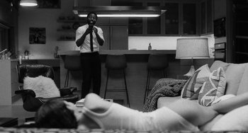 Movie still from “Malcolm & Marie” (2021), directed by Sam Levinson – A black and white photo of a man taking a picture of a woman laying in bed; Medium shot, Over the shoulder angle