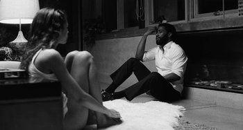 Movie still from “Malcolm & Marie” (2021), directed by Sam Levinson – A man sitting on the ground next to a woman; Medium shot, Over the shoulder angle