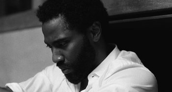 Movie still from “Malcolm & Marie” (2021), directed by Sam Levinson – A black and white photo of a man looking down; Close Up shot, Low angle