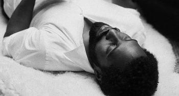 Movie still from “Malcolm & Marie” (2021), directed by Sam Levinson – A black and white photo of a man laying on the ground; Close Up shot, Overhead angle