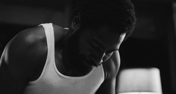 Movie still from “Malcolm & Marie” (2021), directed by Sam Levinson – A black and white photo of a man looking down; Close Up shot, Low angle