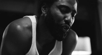 Movie still from “Malcolm & Marie” (2021), directed by Sam Levinson – A black and white photo of a man smoking a cigarette; Extreme Close Up shot, Low angle