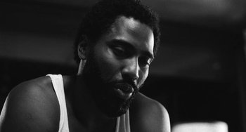 Movie still from “Malcolm & Marie” (2021), directed by Sam Levinson – A black and white photo of a man smoking a cigarette; Close Up shot, Low angle