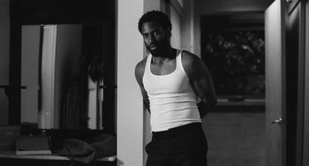 Movie still from “Malcolm & Marie” (2021), directed by Sam Levinson – A black and white photo of a man in a tank top; Medium shot, Low angle