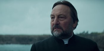 Movie still from “Marianne” (2019), created by Samuel Bodin – An older man with a beard wearing a black jacket; Close Up shot, Low angle