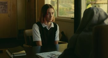 Movie still from “Lady Bird” (2017), directed by Greta Gerwig – A woman sitting at a table in front of a window; Medium shot, Over the shoulder angle