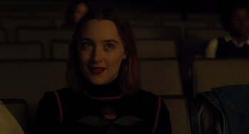Movie still from “Lady Bird” (2017), directed by Greta Gerwig – A woman sitting in a dark room in front of a projector screen; Medium shot, Over the shoulder angle