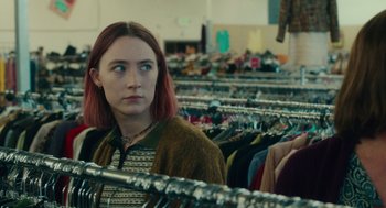 Movie still from “Lady Bird” (2017), directed by Greta Gerwig – A woman standing next to a row of racks of clothes; Medium shot, Over the shoulder angle