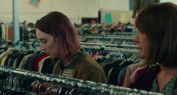 Movie still from “Lady Bird” (2017), directed by Greta Gerwig – A woman with pink hair is looking at clothes on a rack; Medium shot, Over the shoulder angle