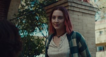 Movie still from “Lady Bird” (2017), directed by Greta Gerwig – A woman with pink hair standing in front of a brick building; Medium shot, Over the shoulder angle