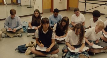 Movie still from “Lady Bird” (2017), directed by Greta Gerwig – A group of students sitting on the floor writing on notepads; Medium shot, High angle