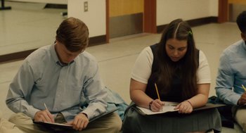 Movie still from “Lady Bird” (2017), directed by Greta Gerwig – Two people sitting on the ground writing on paper; Medium shot, High angle