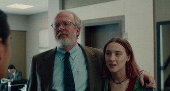 Movie still from “Lady Bird” (2017), directed by Greta Gerwig – A man standing next to a woman in a room; Medium shot, Low angle