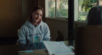 Movie still from “Lady Bird” (2017), directed by Greta Gerwig – A person sitting at a table in front of a window; Medium shot, Over the shoulder angle