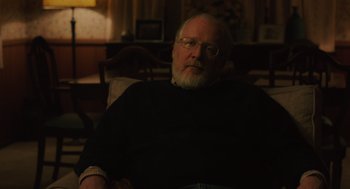 Movie still from “Lady Bird” (2017), directed by Greta Gerwig – An older man sitting in a chair in a room; Medium shot, Over the shoulder angle