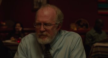 Movie still from “Lady Bird” (2017), directed by Greta Gerwig – An older man wearing glasses and a shirt and tie; Close Up shot, Over the shoulder angle