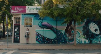 Movie still from “Lady Bird” (2017), directed by Greta Gerwig – A woman standing on the side of a building next to a tree; Extreme Wide shot, Low angle