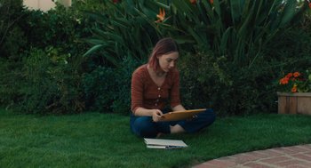 Movie still from “Lady Bird” (2017), directed by Greta Gerwig – A woman sitting in the grass with a tablet; Medium shot, High angle