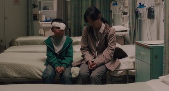 Movie still from “Lady Bird” (2017), directed by Greta Gerwig – A woman sitting next to a young boy in a hospital room; Medium shot, High angle