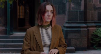 Movie still from “Lady Bird” (2017), directed by Greta Gerwig – A woman with pink hair standing in front of a building; Medium shot, Over the shoulder angle