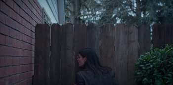 Movie still from “Marianne” (2019), created by Samuel Bodin – A woman leaning against a wooden fence looking out; Medium shot, Low angle