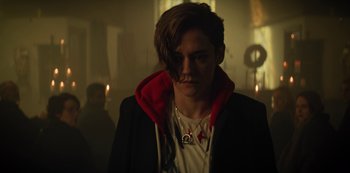 Movie still from “Marianne” (2019), created by Samuel Bodin – A man with a red hood is standing in a dark room; Close Up shot, Over the shoulder angle