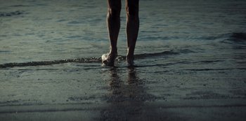 Movie still from “Marianne” (2019), created by Samuel Bodin – A man standing in the water on the beach; Extreme Close Up shot, Low angle