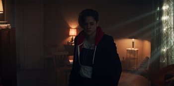 Movie still from “Marianne” (2019), created by Samuel Bodin – A person standing in a dark room with a lamp; Medium shot, Over the shoulder angle