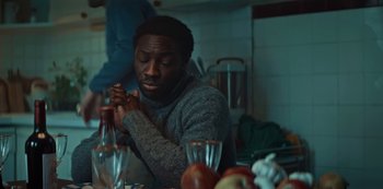 Movie still from “Marianne” (2019), created by Samuel Bodin – A man sitting at a table with a glass of wine; Medium shot, Over the shoulder angle