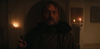 Movie still from “Marianne” (2019), created by Samuel Bodin – A man with a beard wearing a monk's robe; Close Up shot, Low angle