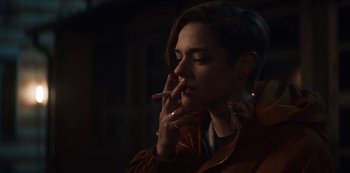 Movie still from “Marianne” (2019), created by Samuel Bodin – A woman is smoking a cigarette in a dark room; Close Up shot, Over the shoulder angle