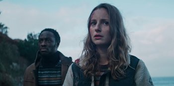 Movie still from “Marianne” (2019), created by Samuel Bodin – A woman with a bruised face standing next to a man with long brown hair; Close Up shot, Low angle