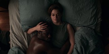 Movie still from “Marianne” (2019), created by Samuel Bodin – A man and a woman laying in a bed; Medium shot, Overhead angle