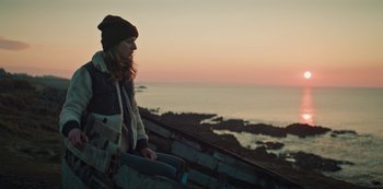 Movie still from “Marianne” (2019), created by Samuel Bodin – A woman sitting on the side of a boat looking out at the ocean; Medium shot, Low angle