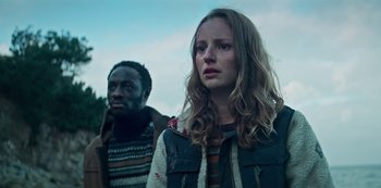 Movie still from “Marianne” (2019), created by Samuel Bodin – Two people standing next to each other on a cloudy day; Close Up shot, Low angle