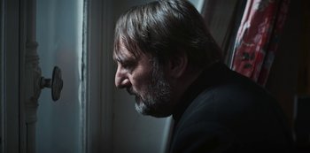 Movie still from “Marianne” (2019), created by Samuel Bodin – A person with a beard looking out a window; Close Up shot, Low angle