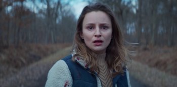 Movie still from “Marianne” (2019), created by Samuel Bodin – A young woman in a sweater and a jacket; Close Up shot, Low angle