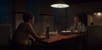 Movie still from “Marianne” (2019), created by Samuel Bodin – Two people sitting at a dinner table at night; Wide shot, Over the shoulder angle