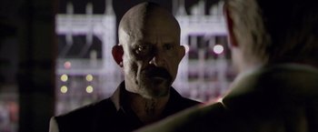 Movie still from “Miami Vice” (2006), directed by Michael Mann – A man with a shaved head is looking at the camera; Close Up shot, Over the shoulder angle