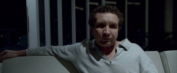 Movie still from “Miami Vice” (2006), directed by Michael Mann – A man with curly hair is sitting in a room; Close Up shot, High angle